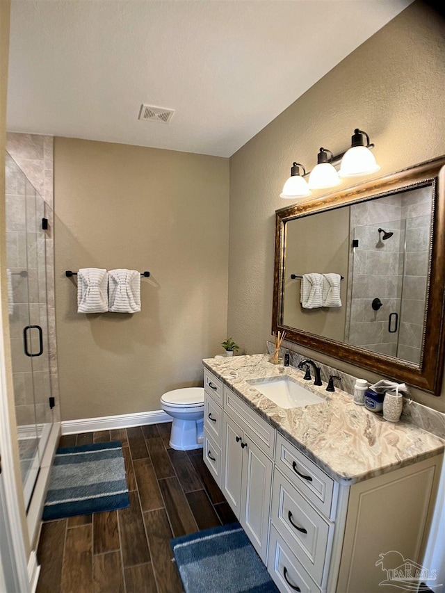full bathroom with wood tiled floor, baseboards, visible vents, a shower stall, and vanity