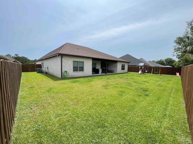 back of house featuring a fenced backyard, a playground, central air condition unit, and a lawn