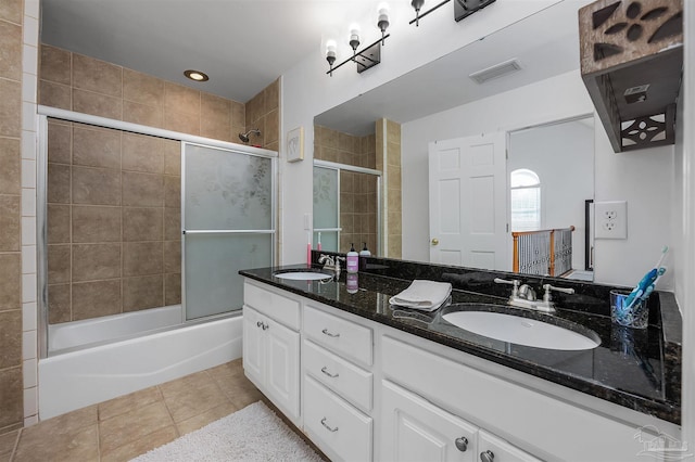 bathroom with tile patterned flooring, bath / shower combo with glass door, and double sink vanity