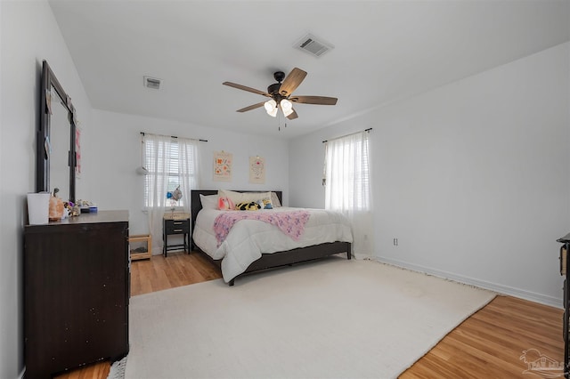 bedroom with ceiling fan, multiple windows, and light hardwood / wood-style flooring