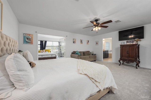 bedroom featuring ensuite bath, light colored carpet, and ceiling fan