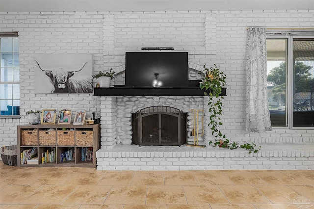 tiled living room featuring a brick fireplace, brick wall, and plenty of natural light