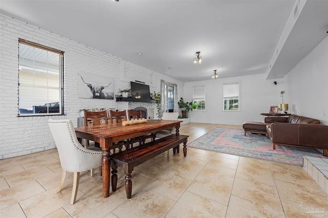 dining area featuring brick wall and light tile patterned floors