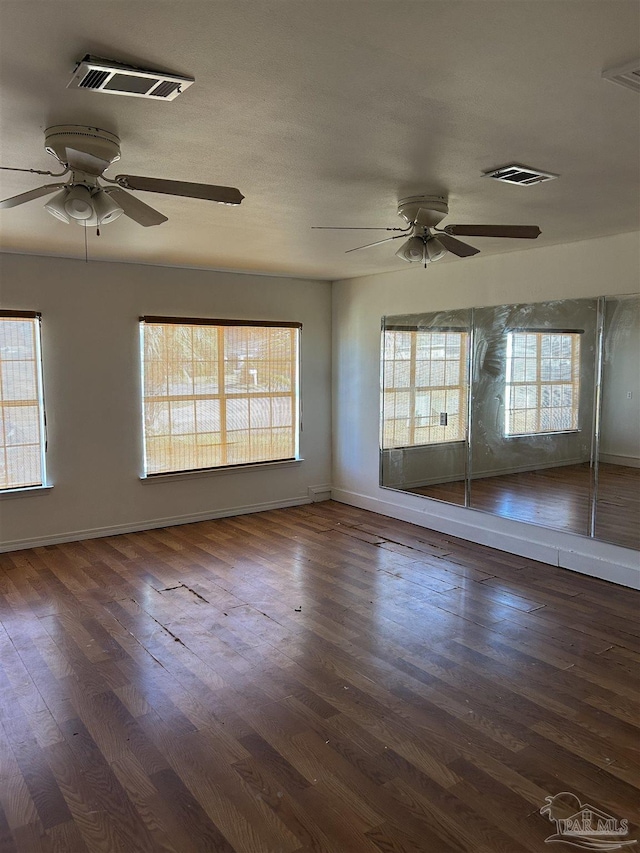 unfurnished room featuring a wealth of natural light, ceiling fan, and dark hardwood / wood-style floors