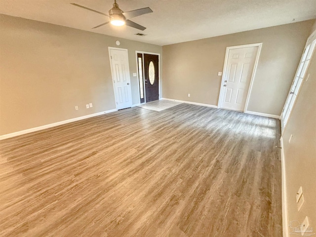 interior space featuring light wood-type flooring, ceiling fan, visible vents, and baseboards