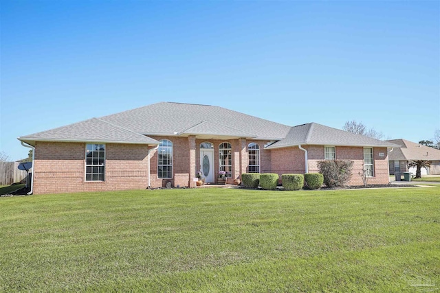 view of front facade featuring brick siding, roof with shingles, and a front yard