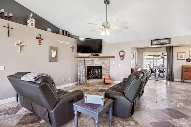 living room with a stone fireplace, baseboards, stone finish flooring, and a ceiling fan