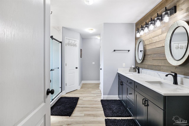 bathroom with double vanity, wood walls, wood finished floors, and a sink