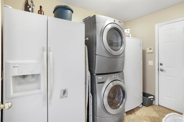 laundry area with water heater, cabinet space, and stacked washer and dryer