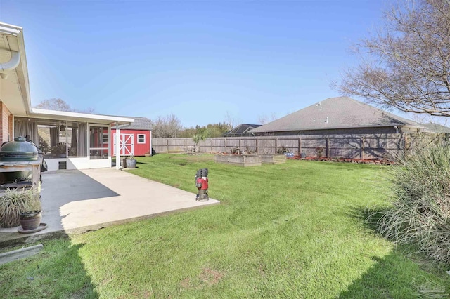 view of yard with a garden, a fenced backyard, a sunroom, an outdoor structure, and a patio area