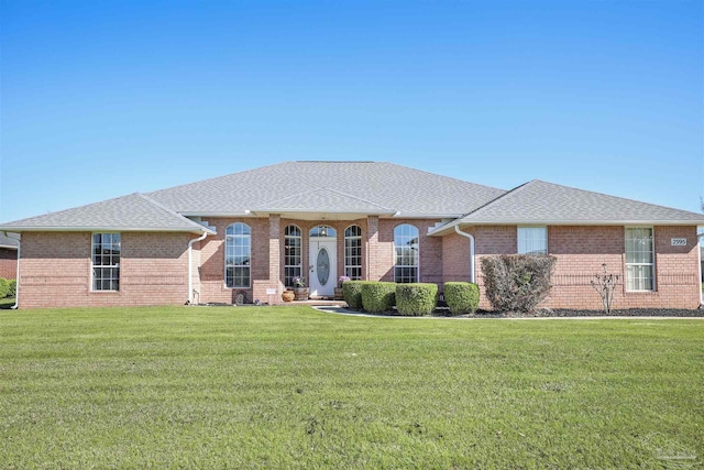 view of front facade featuring brick siding, a front lawn, and a shingled roof