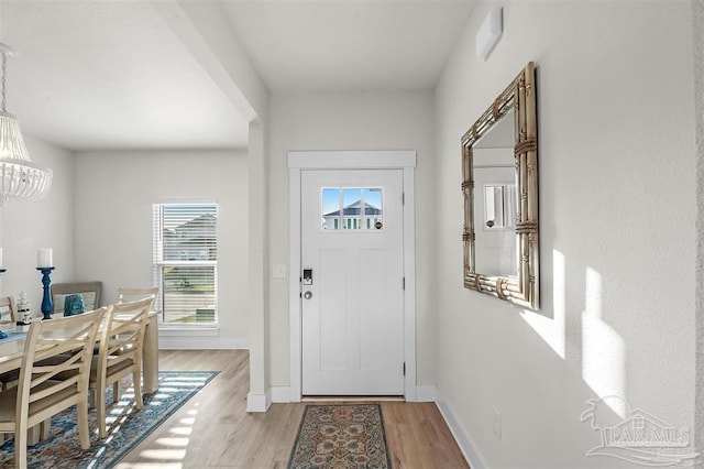 entrance foyer with a notable chandelier, light wood-type flooring, and baseboards