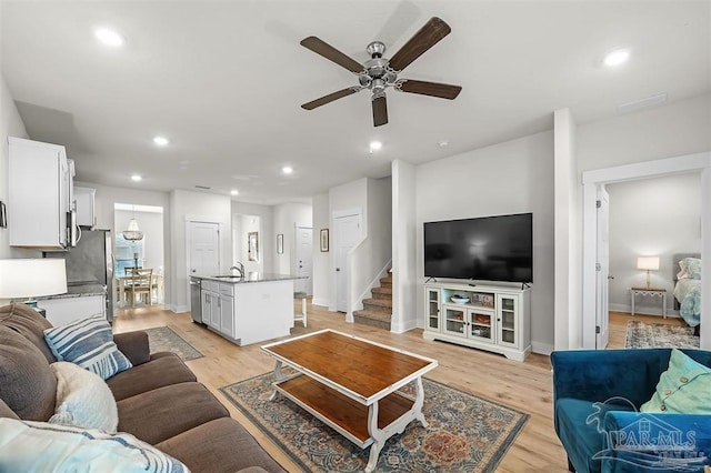 living room with stairs, light wood finished floors, and recessed lighting