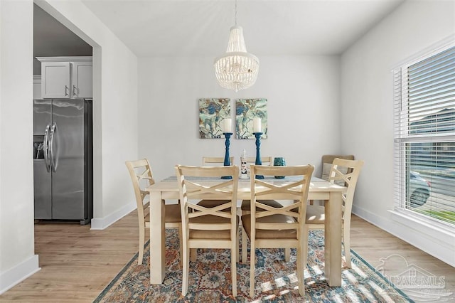 dining space featuring baseboards, a notable chandelier, and light wood finished floors