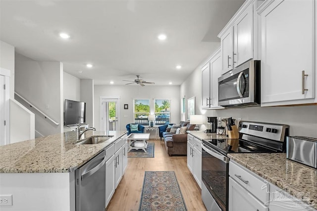 kitchen featuring stainless steel appliances, light wood finished floors, a sink, and white cabinetry