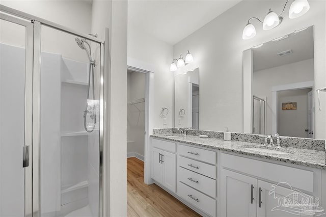 bathroom featuring a stall shower, visible vents, a sink, and wood finished floors