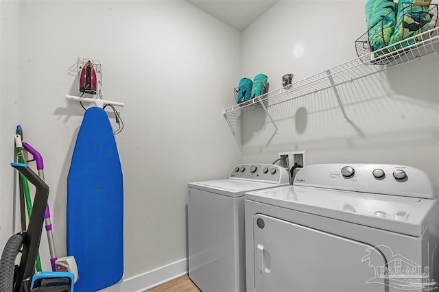 clothes washing area featuring laundry area, washer and clothes dryer, baseboards, and light wood finished floors