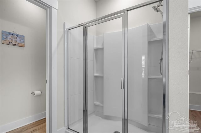 bathroom featuring a stall shower, baseboards, and wood finished floors