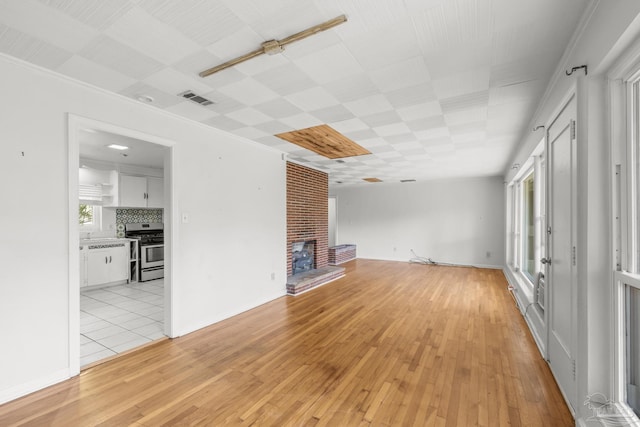 unfurnished living room featuring light wood finished floors, a fireplace, and visible vents