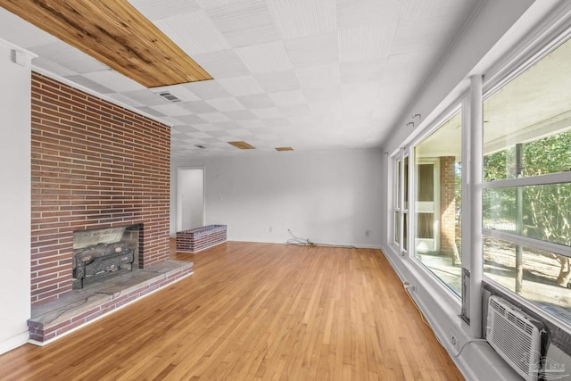 unfurnished living room with a fireplace, visible vents, and hardwood / wood-style floors