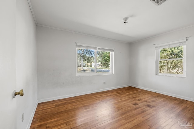 spare room with baseboards, hardwood / wood-style floors, plenty of natural light, and crown molding