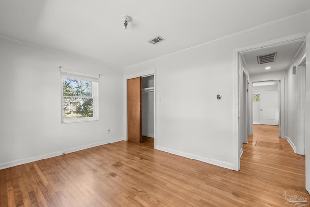 unfurnished bedroom with light wood finished floors, baseboards, visible vents, and crown molding