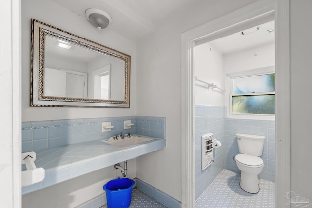 bathroom featuring tile patterned flooring, a wainscoted wall, tile walls, and toilet