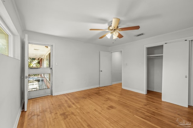 unfurnished bedroom featuring baseboards, light wood-style flooring, visible vents, and crown molding