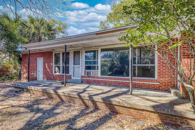 rear view of property with a porch and brick siding