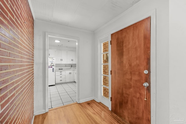 corridor featuring brick wall, light wood finished floors, and crown molding