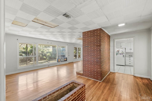 unfurnished living room with visible vents, baseboards, and hardwood / wood-style flooring