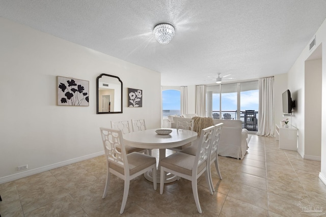 tiled dining space with a textured ceiling and ceiling fan