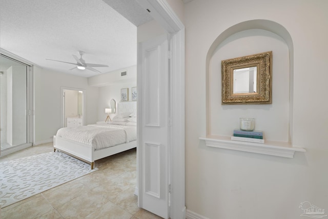 bedroom with a textured ceiling, ceiling fan, and light tile patterned floors