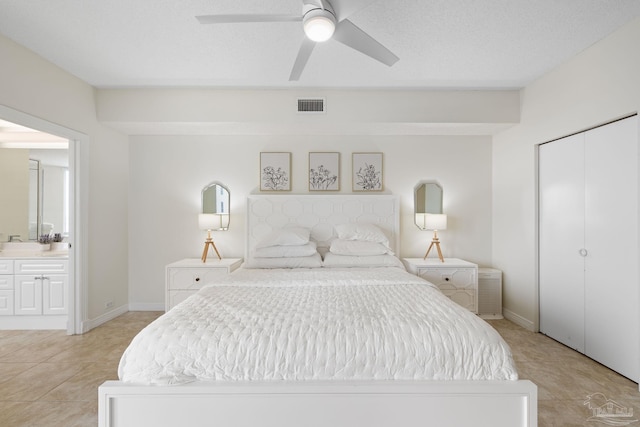 bedroom featuring ensuite bath, a textured ceiling, light tile patterned floors, ceiling fan, and a closet