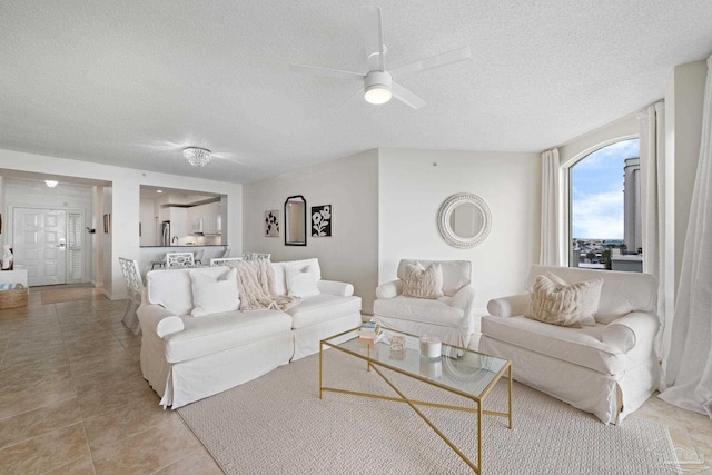 tiled living room with a textured ceiling and ceiling fan