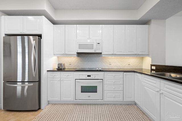 8501 Gulf Blvd Unit 3B, Navarre Beach, FL 32566 - kitchen with white appliances, dark countertops, tasteful backsplash, and white cabinetry