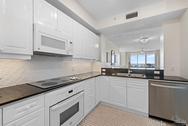 8501 Gulf Blvd Unit 3B, Navarre Beach, FL 32566 - kitchen featuring white appliances, a sink, dark countertops, and white cabinets