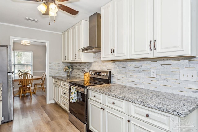 kitchen featuring white cabinets, decorative backsplash, wall chimney exhaust hood, appliances with stainless steel finishes, and light wood-style floors