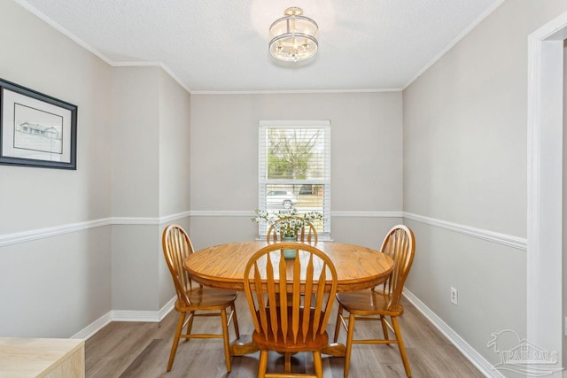 dining area featuring light wood-style flooring, baseboards, and a textured ceiling