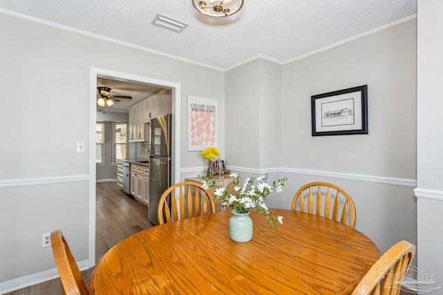 dining room featuring dark wood-style flooring, visible vents, crown molding, and a textured ceiling