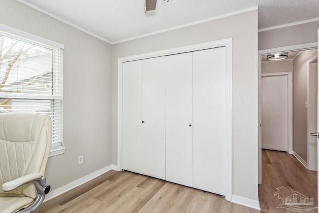 unfurnished bedroom featuring crown molding, a closet, light wood-style floors, a textured ceiling, and baseboards