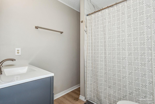 bathroom with a textured ceiling, curtained shower, wood finished floors, vanity, and baseboards