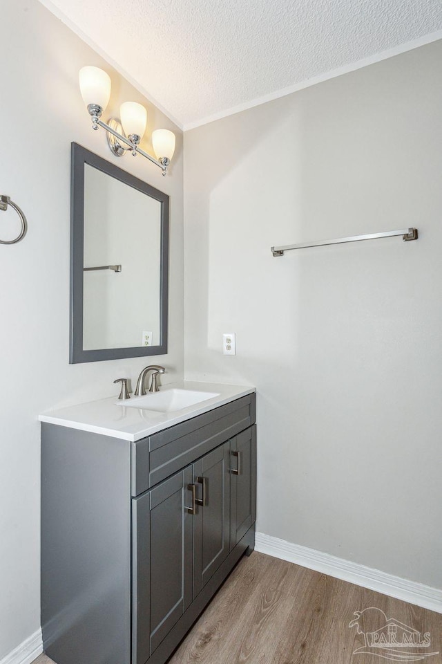 bathroom featuring baseboards, vanity, a textured ceiling, and wood finished floors