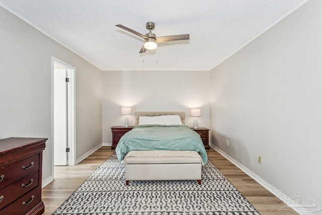 bedroom with light wood-style floors, baseboards, and a textured ceiling