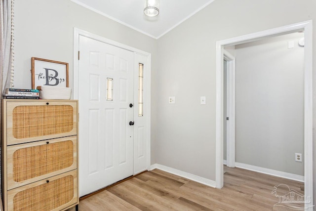 entrance foyer featuring ornamental molding, light wood-style flooring, and baseboards