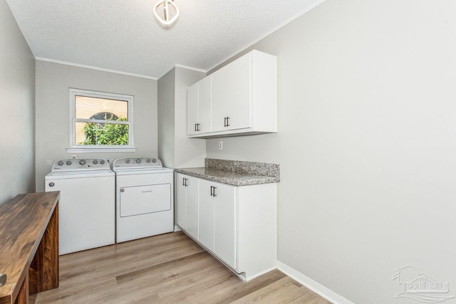 clothes washing area with light wood-type flooring, cabinet space, a textured ceiling, and washing machine and clothes dryer