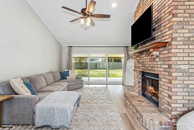 living room featuring a ceiling fan, a fireplace, high vaulted ceiling, and wood finished floors