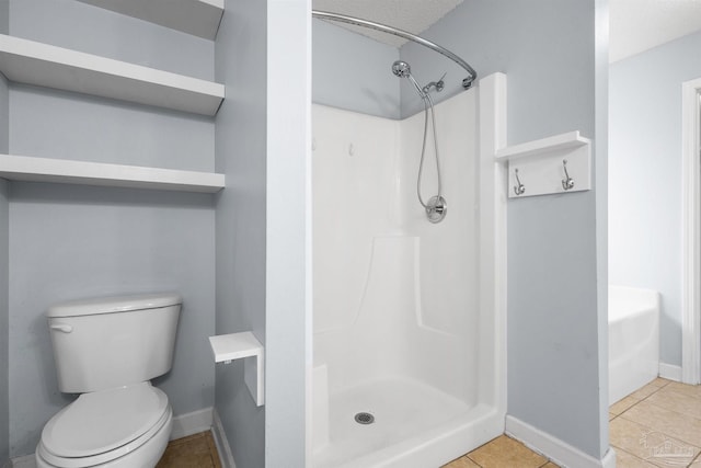 full bathroom with baseboards, tile patterned flooring, a stall shower, and toilet