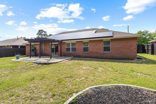 back of property with a pergola, a patio area, a fenced backyard, roof mounted solar panels, and brick siding