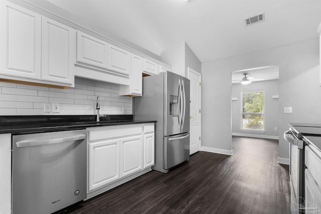 kitchen with stainless steel appliances, dark countertops, visible vents, backsplash, and dark wood-type flooring